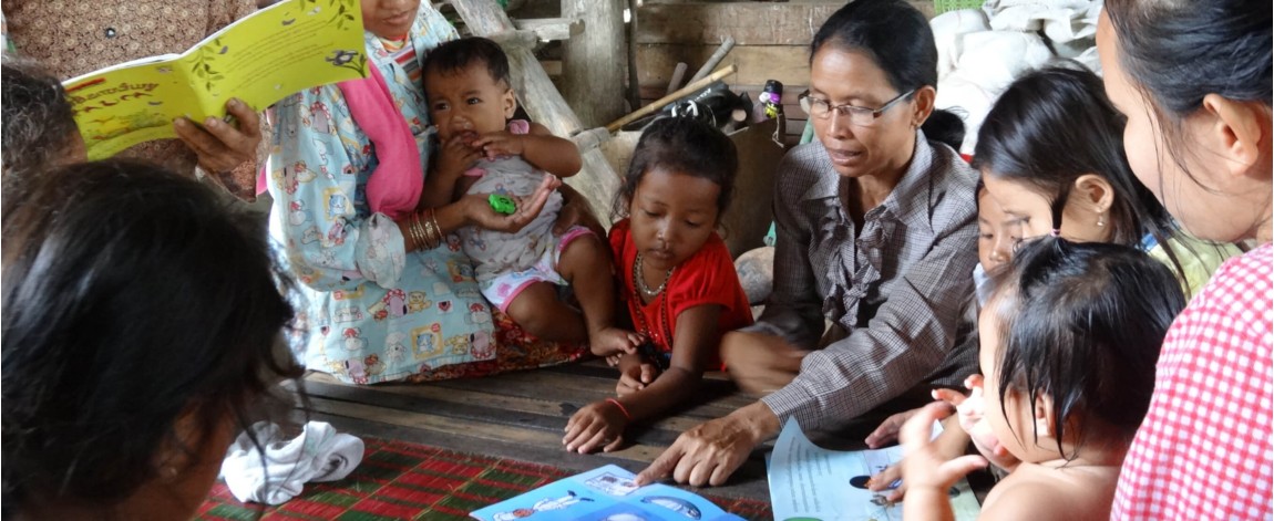 Adult teaching a group children to read