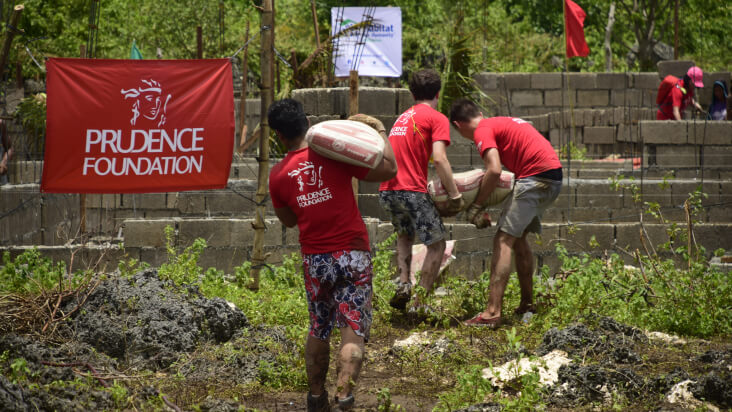 Prudential volunteers carry supplies through field.
