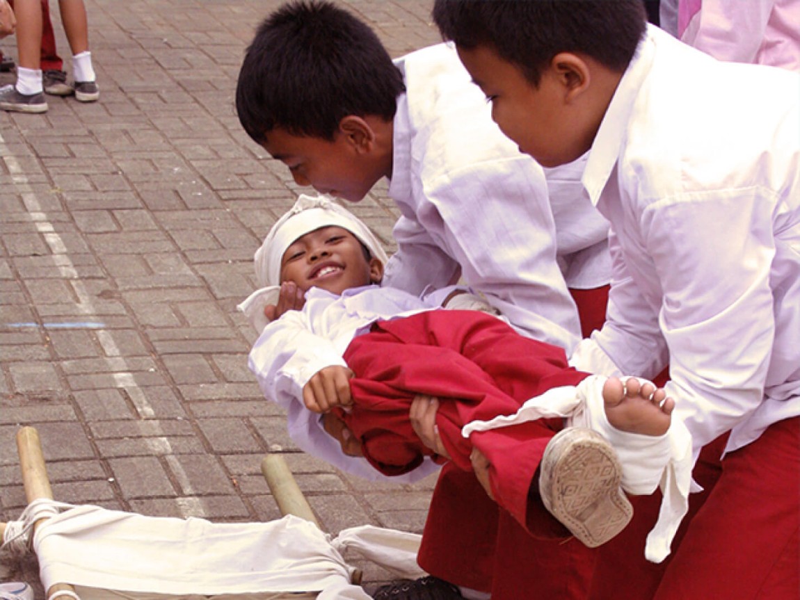 Children practising first aid on a classmate.