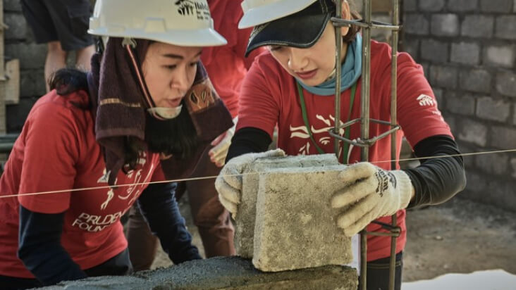 Two PRUVolunteers build the wall for a house